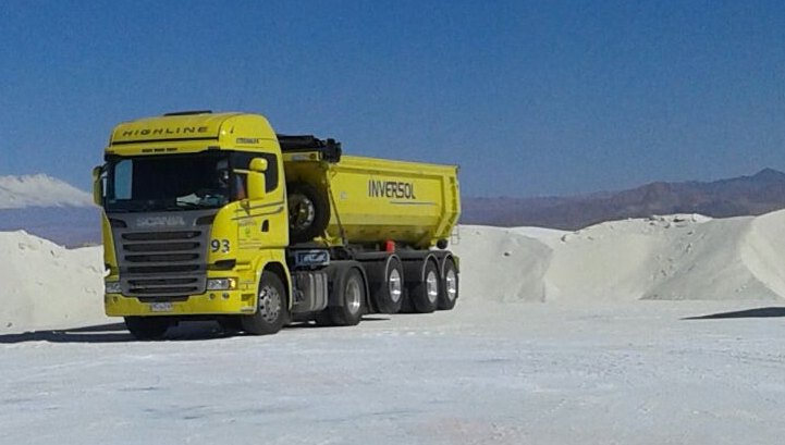 Camión de Logística Inversol cargado sobre un salar del altiplano boliviano, con la cordillera al fondo